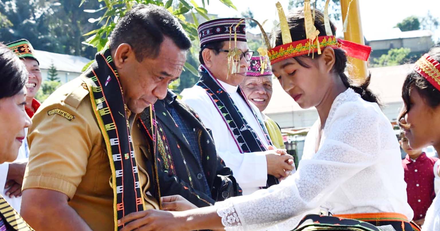 Bupati Manggarai Herybertus Geradus Laju Nabit menerima pengalungan kain tenun sebagai bagian dari prosesi penyambutan adat saat menghadiri Puncak Syukuran 50 Tahun (Pesta Emas) Paroki Santo Antonius Padua Ri'i di Desa Bea Mese, Kecamatan Cibal, Kabupaten Manggarai, Senin, 27 Juli 2026.