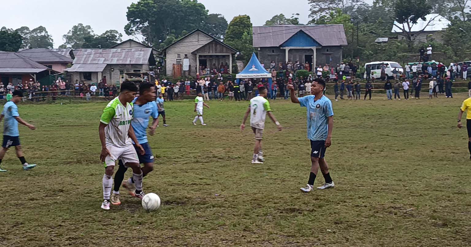 Ribuan penonton menggunakan payung menyaksikan partai final Turnamen FX Cup II 2026 antara Misio Unika FC dan Harta FC di Lapangan Paroki Poka, Kecamatan Wae Ri'i, Kabupaten Manggarai.